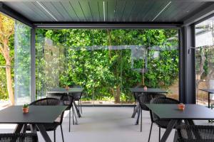 a cafeteria with tables and chairs and a large window at Domìa Boutique Hotel e Cucina in Mondello