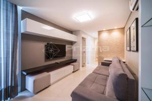ein Wohnzimmer mit einem Sofa und einem TV in der Unterkunft Varandas 405 A · Apartamento em Condomínio de luxo frente ao mar . in Bombinhas