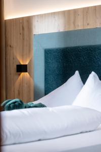 a bed with white sheets and a light on a wall at Apartments Dorfbäck in Stumm