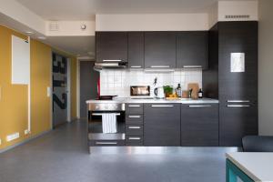 a kitchen with dark brown cabinets and a stove at Rumi Hostel in Trondheim