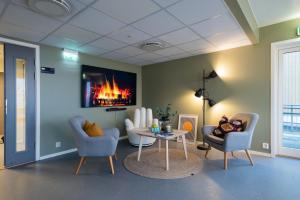 a living room with two chairs and a table and a fireplace at Rumi Hostel in Trondheim