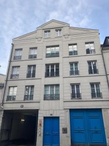 un gran edificio blanco con puertas azules en Studio calme et éclairé proche de Nation C en París