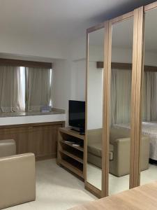 1 dormitorio con 1 cama, TV y espejo en Flat hotel saint moritz, en Brasilia