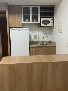 a kitchen with a white refrigerator and a microwave at Flat hotel saint moritz in Brasília
