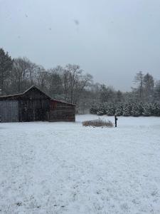 un campo cubierto de nieve con un granero y una boca de incendios en FRENCH WOODS FARMHOUSE Catskills Upper Delaware River Hancock NY, en Hancock