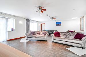 a living room with two couches and a ceiling fan at Detached bungalow with 7 bedrooms in Luton