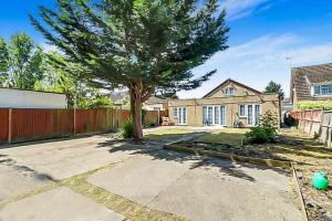 a house with a tree in the driveway at Detached bungalow with 7 bedrooms in Luton