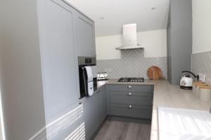 a kitchen with white cabinets and a stove top oven at The Hideout, IH4AOXF in Middlesbrough