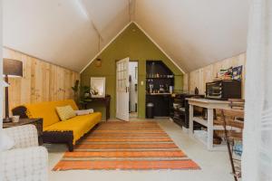 a living room with a yellow couch and a kitchen at Southern Yurts in Botrivier