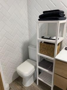 a bathroom with a toilet and a shelf with towels at El Embarcadero in Boó de Piélagos