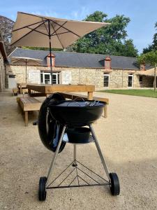 - un barbecue avec un parasol devant une table dans l'établissement Le Château de La Beauvais, à Piré-sur-Seiche