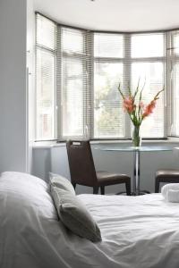 a bedroom with a bed and a table with a vase of flowers at Superfast WiFi studio, bathroom & own entrance in Brighton & Hove