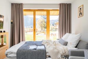 a bedroom with a bed and a couch and a window at Polana Resort by LoftAffair in Kościelisko