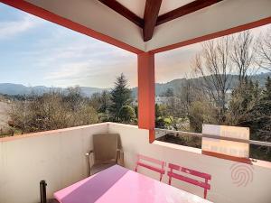 une terrasse couverte avec une table et des chaises roses ainsi que des montagnes dans l'établissement Appartement Lamalou-les-Bains, 2 pièces, 2 personnes - FR-1-451-107, à Lamalou-les-Bains