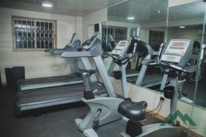 een fitnessruimte met loopbanden en crosstrainers bij Ange Hill Hotel in Accra