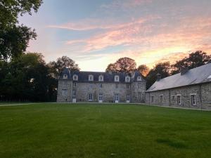 un ancien bâtiment en pierre avec une grande pelouse dans l'établissement Le Château de La Beauvais, à Piré-sur-Seiche