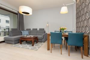 a living room with a table and blue chairs at Warsaw Mokotów Apartment Chodkiewicza by Renters in Warsaw