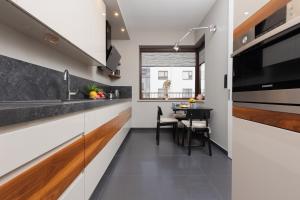 a kitchen with white cabinets and a dining table at Warsaw Mokotów Apartment Chodkiewicza by Renters in Warsaw