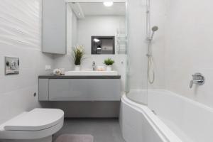 a white bathroom with a tub and a toilet and a sink at Warsaw Mokotów Apartment Chodkiewicza by Renters in Warsaw