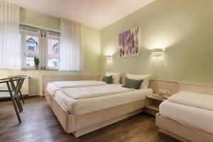Un dormitorio con dos camas y una mesa y dos ventanas. en Hotel Kunterbunt in Würzburger Innenstadt, en Würzburg