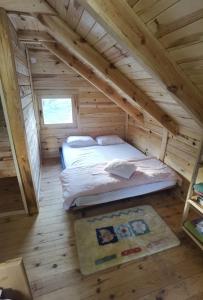 a bedroom in a log cabin with a bed in the attic at Raj na Drini kuće sa bazenom 