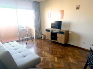 uma sala de estar com um sofá branco e uma televisão em Departamento con gran vista en el casco histórico em Assunção