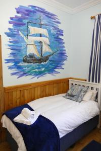 a bedroom with a painting of a ship on the wall at Peerboom Guesthouse in Fouriesburg