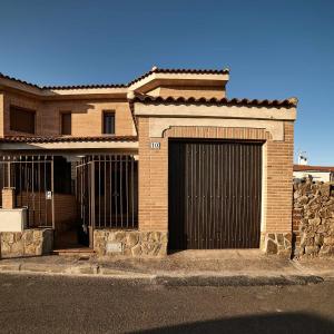 une maison en briques avec un portail et un garage dans l'établissement La Casa del Olivo, à Navahermosa