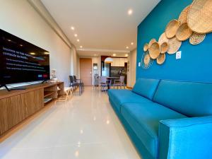 sala de estar con sofá azul y TV de pantalla plana en Residencial SAN MARINO BEIRA MAR, en Ilhéus