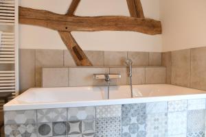 uma banheira na casa de banho com tectos em madeira em Vakantiewoningen - Buitenverblijf Huiskenshof Zuid-Limburg em Klimmen