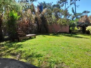 un banco del parque sentado en un patio con césped en Punta Avellaneda, en Punta del Diablo
