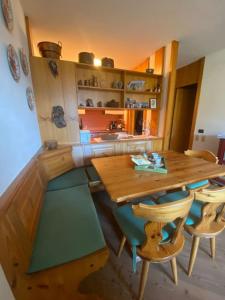 a kitchen with a wooden table and chairs at Encia's Home Dolomiti in Castello di Fiemme