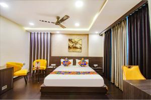 コルカタにあるFabHotel Prime Kzar Corporateのベッドルーム(大型ベッド1台、黄色い椅子付)