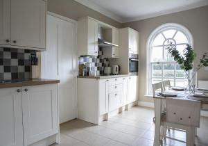 eine Küche mit weißen Schränken, einem Tisch und einem Fenster in der Unterkunft Walshford Lodge in Cowthorpe