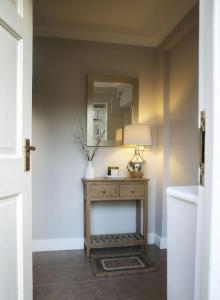 a hallway with a table with a lamp and a mirror at Walshford Lodge in Cowthorpe