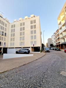 a street with cars parked in front of a building at Luxe-Design Imperio II- Petit Déjeuner 5min de la Mer in Praia