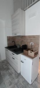 eine weiße Küche mit Spüle und Kühlschrank in der Unterkunft Seaside Sartoria in Bari