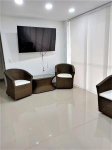 sala de estar con sillas de mimbre y TV de pantalla plana en Acogedor, Gran Vista a las Montañas y a la Ciudad! en Santa Fe de Antioquia