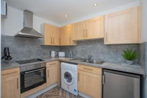 cocina con armarios de madera y lavadora en Tiramisu House - Luxury 2 Bed Apartment in Aberdeen Centre, en Aberdeen