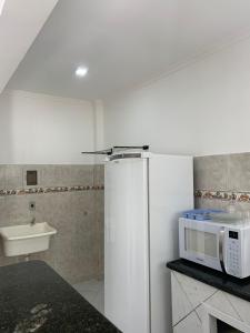 a kitchen with a microwave and a sink at Pousada Bravo in Balneário Camboriú