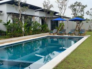 una piscina frente a una casa con sillas y sombrillas en IBI bali, en Banjar