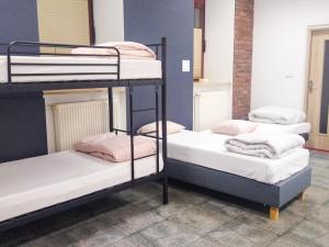 3 łóżka piętrowe w pokoju wieloosobowym z różowymi ręcznikami w obiekcie Music Hostel Piotrkowska w Łodzi