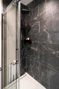 a bathroom with a shower with black marble tiles at Apartament Wielka Turnia by Apart Concept Podhale in Kościelisko