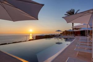 パンテレリアにあるPantelleria Dream Resortのパラソル付きのプールと夕日の海