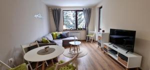 a living room with a couch and a table and a tv at Pine Tree Apartment / Borovets Gardens in Borovets