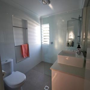 uma casa de banho com um WC branco e um lavatório. em OXLEY Private Heated Mineral Pool & Private Home em Brisbane