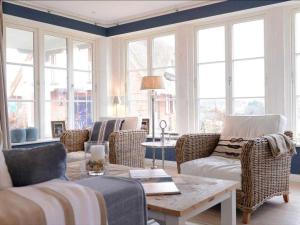 a living room with chairs and a table and windows at Nantucket Blue in Groß Schwansee