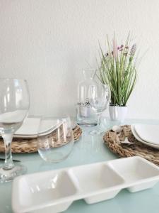 a table with glasses and plates and flowers on it at Gemütliches helles Appartement in Dresden