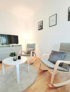 a living room with two chairs and a table and a tv at Gemütliches helles Appartement in Dresden