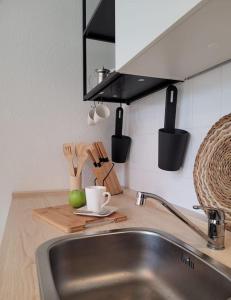 a kitchen counter with a sink and a cup on a cutting board at Gemütliches helles Appartement in Dresden